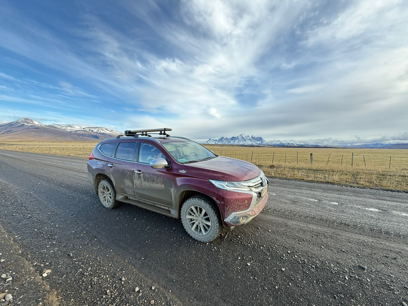 Patagonia Line Mitsubishi Montero Sport on a Patagonian gravel road with the Torres del Paine massif in the distance